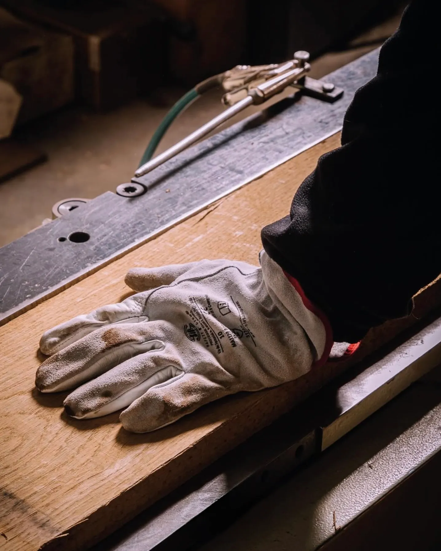Gloved hand on a plank at the workbench