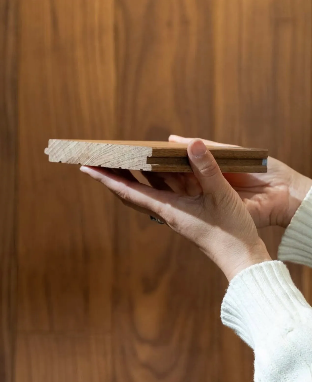 Hands holding a GIANT solid wood plank, showing its tongue and groove